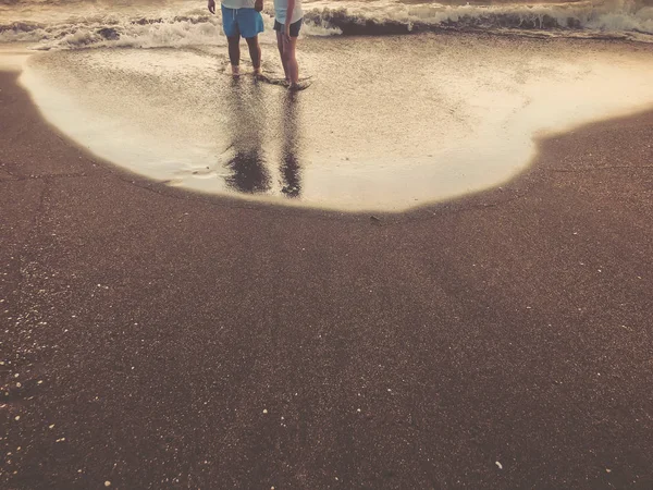 Odraz lidí stojící na pobřeží. Třpytu na písečné pláži. Letní slunný den, písčité pozadí — Stock fotografie