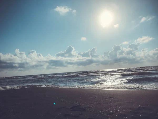 Vista sul mare, cielo e nuvole durante il tramonto. Onde scintillanti su una spiaggia di sabbia. Estate giornata di sole, sfondo acqua — Foto Stock