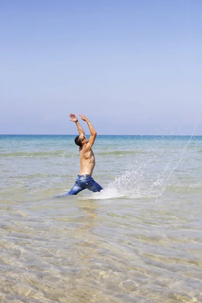 Joven musculoso posando y salpicando en el mar — Foto de Stock