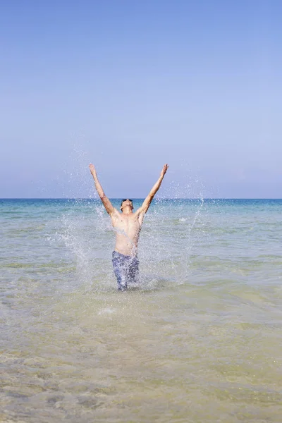Jeune homme musclé posant et éclaboussant dans la mer — Photo