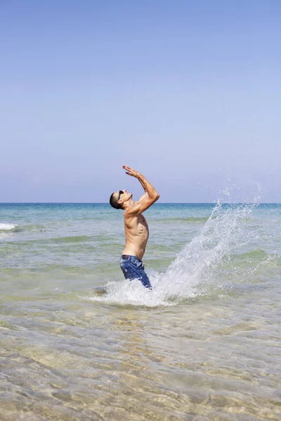 Joven musculoso posando y salpicando en el mar —  Fotos de Stock
