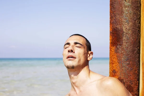 Jonge gespierde man rusten en poseren op het strand — Stockfoto
