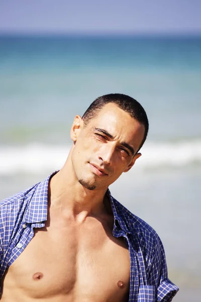 young muscular man resting and posing on the beach