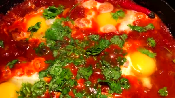 Shakshouka of shakshuka is een Noord-Afrikaans Joods gerecht van eieren gepocheerd in een saus van tomaten, chilipepers en uien, vaak gekruid met komijn. — Stockvideo