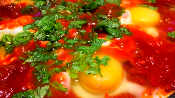 Shakshouka vagy shakshuka egy észak-afrikai zsidó eredetű étel tojás buggyant egy szósz paradicsom, chili paprika, és hagyma, gyakran fűszerezett köménnyel. — Stock videók