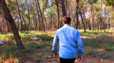 Koşucu adam ormanda koşuyor. Park yolunda koş. Yazın yeşil ormandan manzarayı takip et.