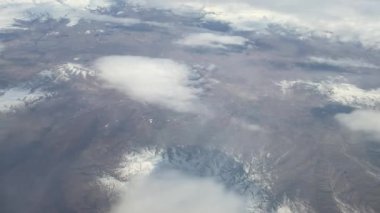 Bulutların üstünde mavi gökyüzü olan uçak penceresinden hava manzarası.