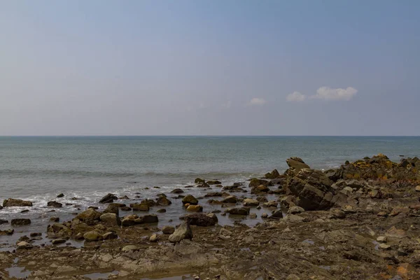 Costa rochosa com mar azul em dia escuro . — Fotografia de Stock