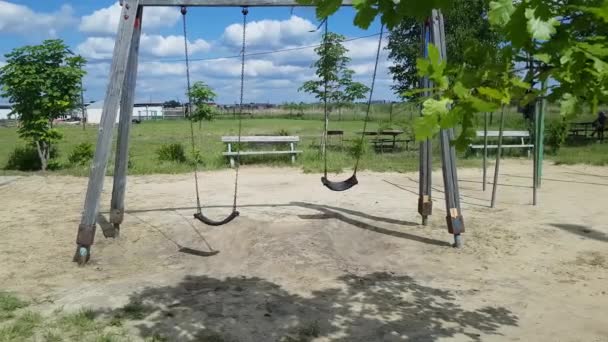 Two children s empty swings on chains moving back and forth in playground — Stock Video