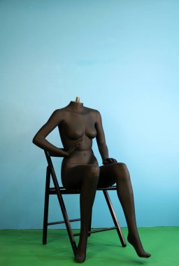 Siyah kadın manken sandalyede oturuyor. 