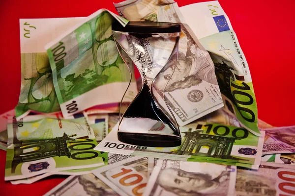Para ve dolar, kırmızı arkaplanda kum saati.