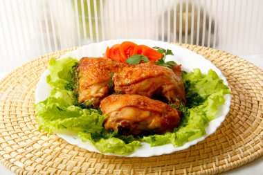 Kızarmış tavuk budu ve salata yaprakları.