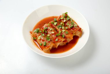 Et ve pilav, domates soslu lahana dolması rulo bir plaka üzerinde.