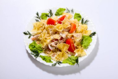 Düdük makarna bir tabak salata ve domates ile üzerine bırakır.