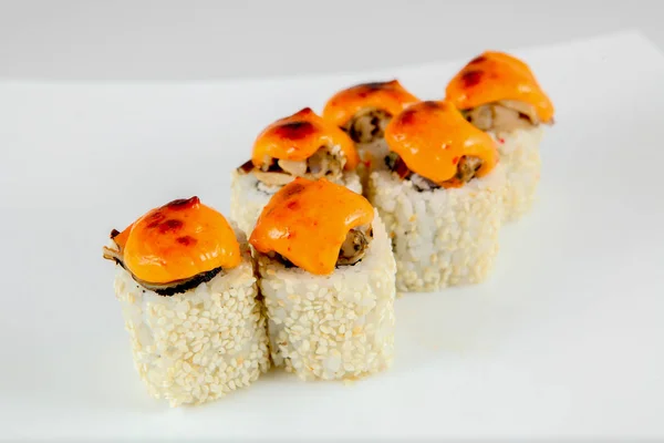 A portion of baked sushi, Japanese cuisine, on a national plate, on a light background.