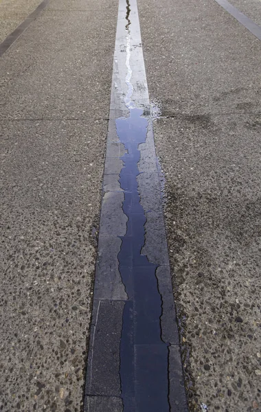 Wet street floor with rain water, water detail and city