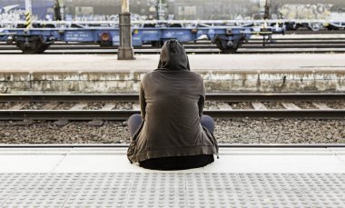 Tren istasyonunda oturan bir kadın, detay trene binmek için bekliyor.