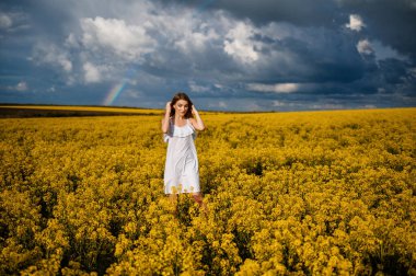 Sarı alanda yürüyen beyaz elbiseli çekici bir sarışın.