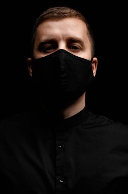 Siyah gömlekli ve siyah maskeli yakışıklı bir adam.