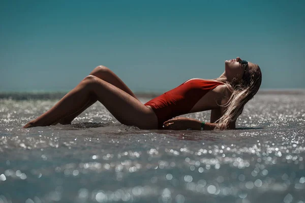 Die Blondine Roten Badeanzug Liegt Strand Wasser — Stockfoto