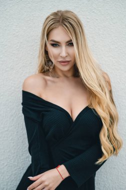 Siyah elbiseli, uzun saçlı, seksi bir sarışın.