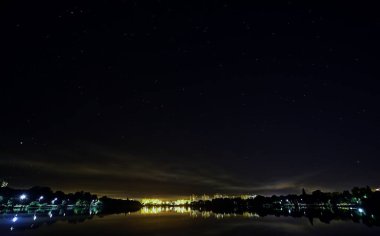 Gece şehrinde göl yıldızlı gökyüzünün altında.