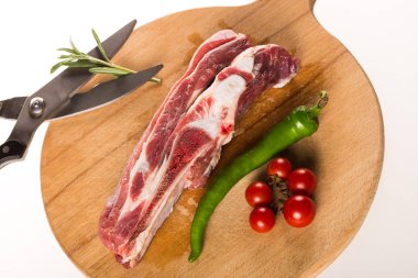 Biber, domates, biberiye ve makas ile ahşap plaka üzerinde pişmemiş kenar