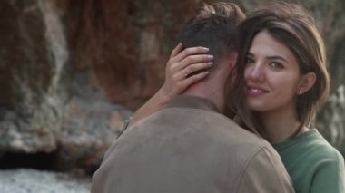 Çift kucaklaşması, kız çerçeveye bakar.