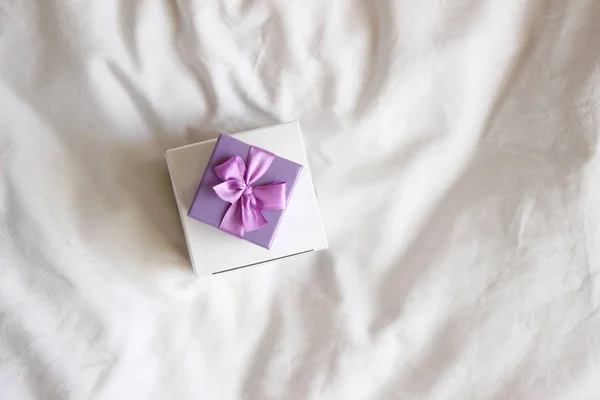 Jewelry Gift boxes, decorated with purple ribbon bow. Valentine\'s Day Gift over white bed linen background. Valentine\'s Gift Closeup.