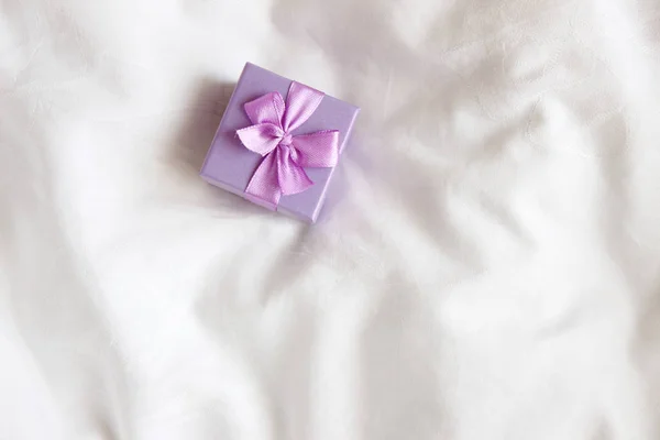 Colorful Jewelry Gift Box. Present box for Holidays, decorated with purple ribbon bow. Valentine\'s Day gift, International Women\'s Day gift on white bed background.