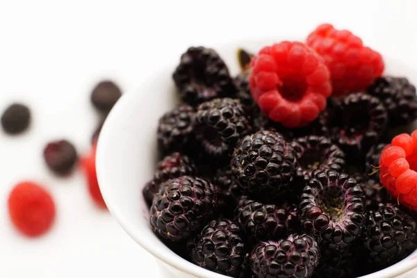 Beyaz arka plan üzerinde olgunlaşmış ahududu ile kupa