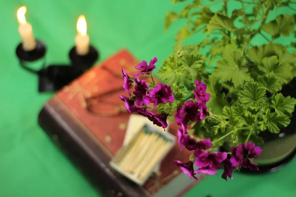 yeşil bir arka plan üzerinde çiçek kitap mumlar ve gözlük ile natürmort