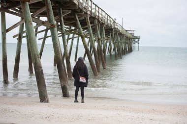 Boardwalk arkasında deniz, plaj ve voleybolu top mahkemeleri ile kadın