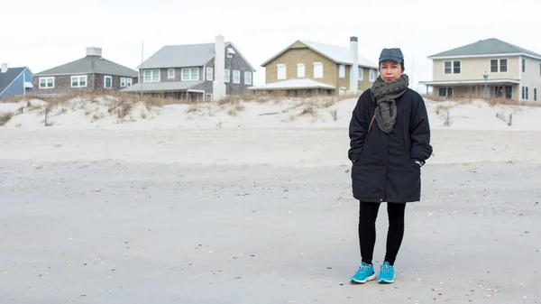 Woman on boardwalk with sea, beach and volley ball courts behind her