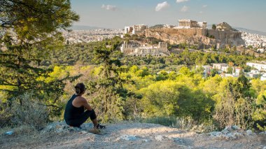 Güneş gözlüğü Parthenon Tapınağı ve Akropolis'in bakarak Philpappos Hill'de oturan kadın