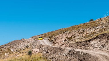 Sarı araba çorak kayalık dağ yolda sürüş