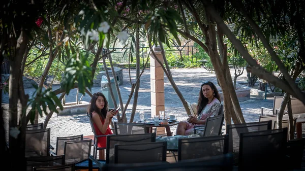 Teen with red dress and mother sitting at cafe table eating breakfast