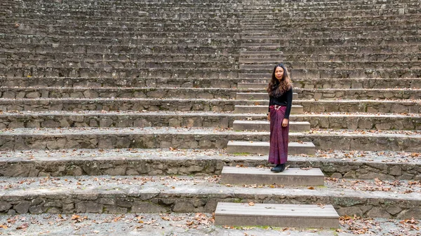 woman in sarong in amphitheater standing on steps looking towards stage