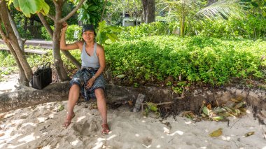 Ağaç gövdesi sahilde oturan kadın