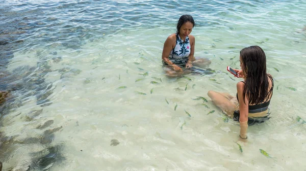 Madre Hija Con Teléfono Móvil Sentadas Mar Playa Rodeadas Peces — Foto de Stock