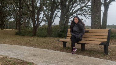 Asya kadın oturma üzerinde Bench içinde Park ile siyah pantolon ve Sneakers