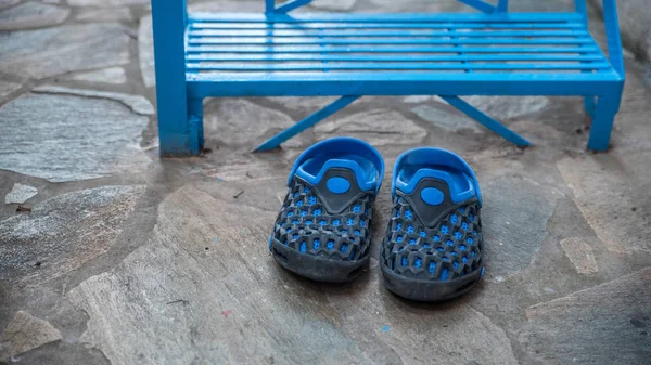 Pair of  blue rubber shoes in front of blue metal stairs in Greek Village