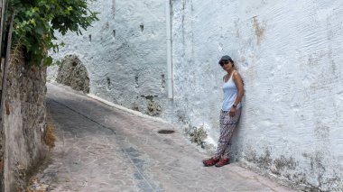 Kadın şapka ve tank top ile Yunan köy sokaklarında yürürken