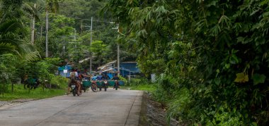 Köydeki erkekler motosiklet sürme ve sebze taşıma