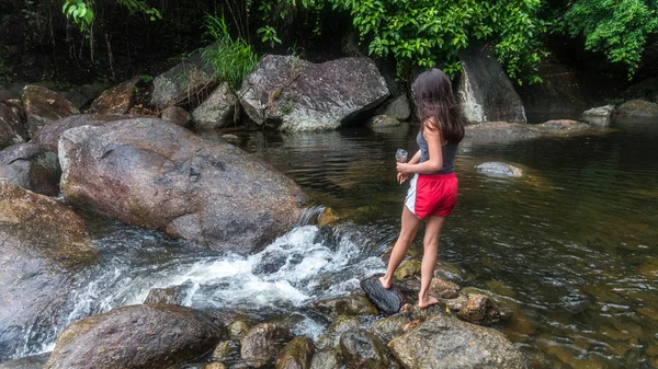 Chica joven alimentando peces junto al río — Foto de Stock