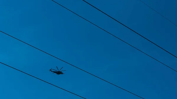 Вертолет пролетает между проводами высокого напряжения — стоковое фото