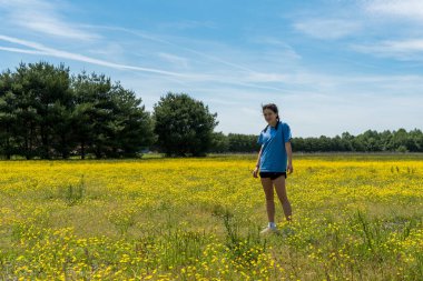 Geniş tarlada sarı çiçekler ve ağaçlarla dikilen gençler.