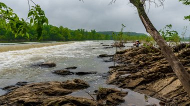 Nehrin kenarındaki kayaların üzerinde oturan kadın