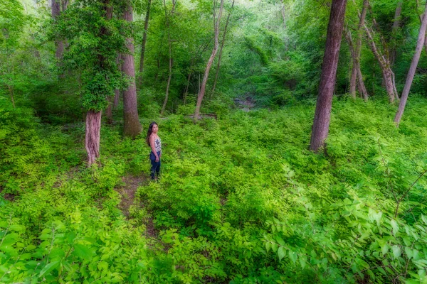 Frau steht im Wald, umgeben von Büschen und Bäumen — Stockfoto