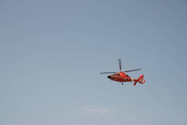 Bulutsuz gökyüzünde uçan turuncu helikopter